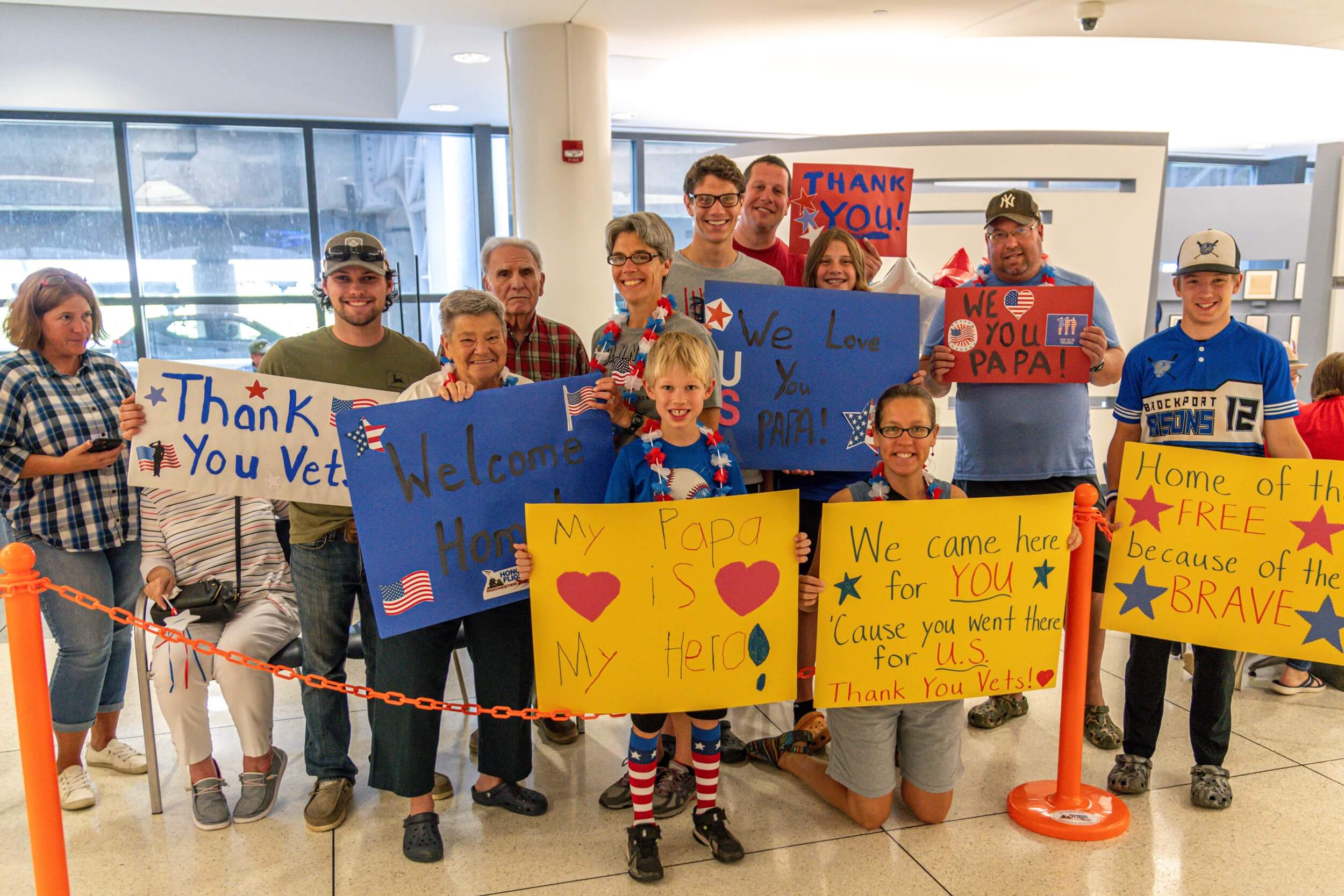 Family at Welcome Home Ceremony with signs for their grandfather