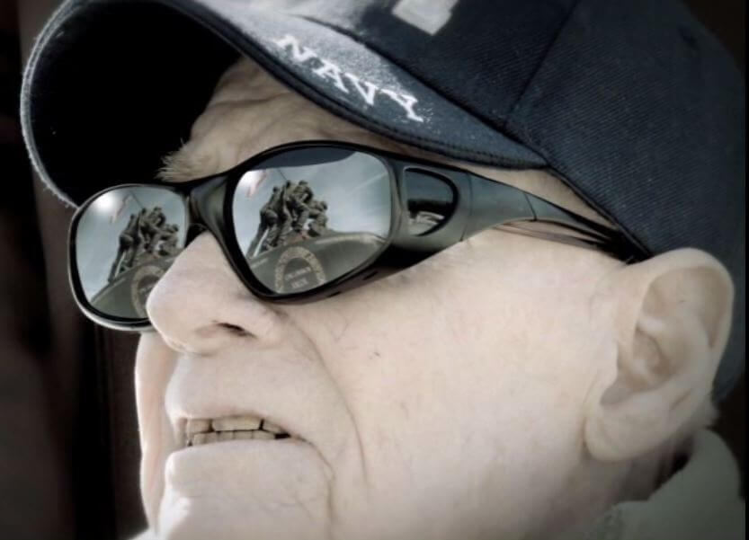 Veteran with sunglasses on and WWII Iwo Jima Memorial statue reflected in sunglasses